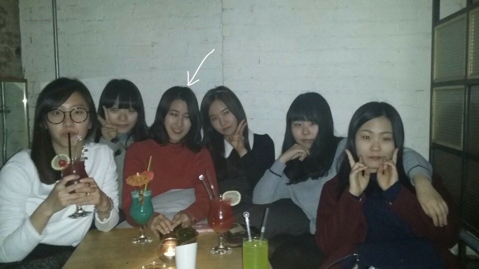 Six Korean girls at a bar table, an arrow pointing to Cathy in the middle